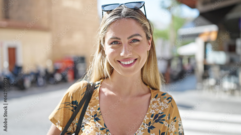 Young blonde woman smiling confident standing at street