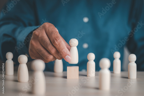 Hands of businessmen choose wooden figure. The concept of choosing leaders for business success. Organization development. Leadership. Personnel selection. Wooden puppet. Wooden peg dolls. wooden doll photo