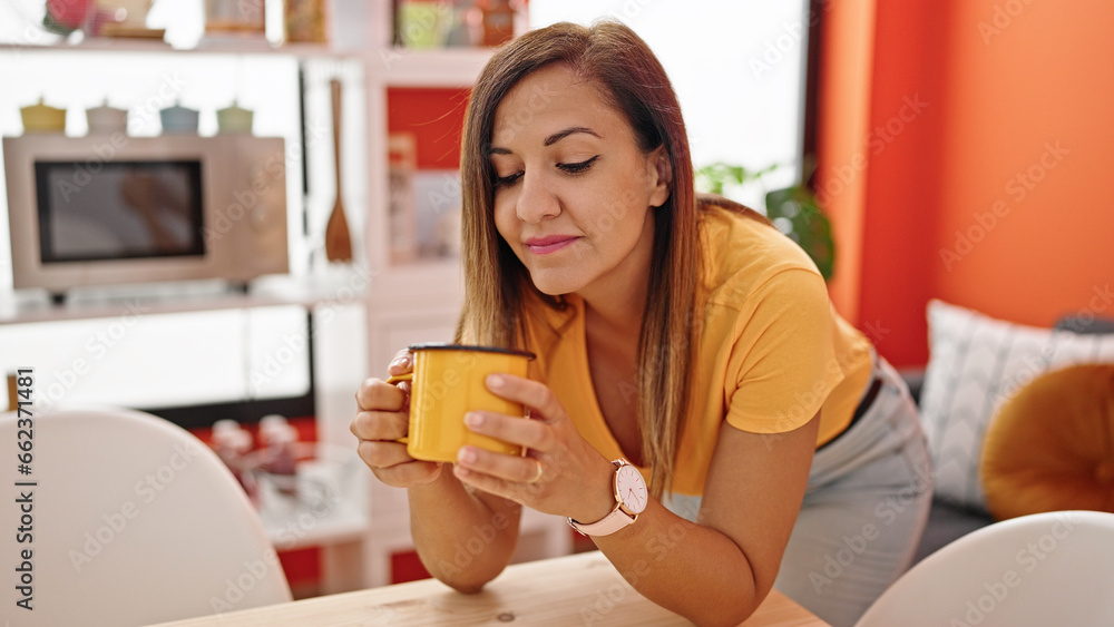 Middle eastern woman drinking coffee leaning on the table at dinning room Middle eastern woman drinking coffee leaning on the table at dinning room