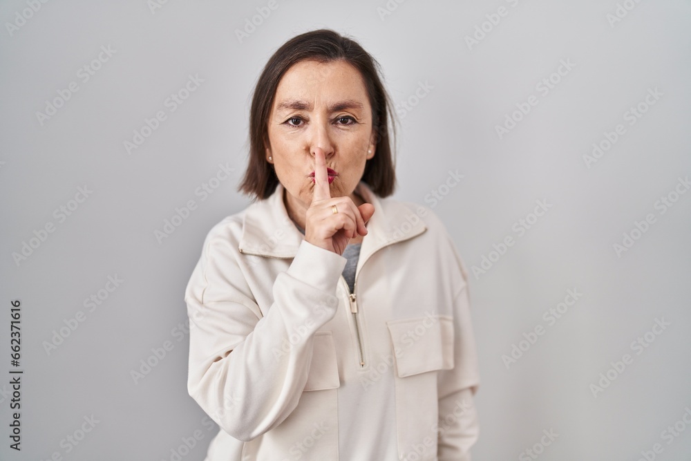 Middle age hispanic woman standing over isolated background asking to be quiet with finger on lips. silence and secret concept. Middle age hispanic woman standing over isolated background asking to be quiet with finger on lips. silence and secret concept.