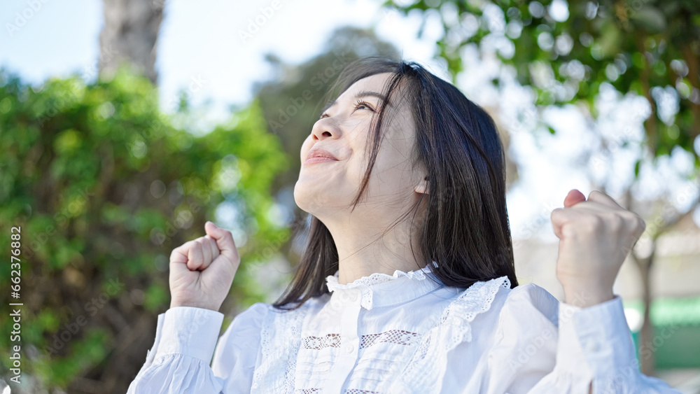 Young chinese woman looking to the sky with winner expressio at park Young chinese woman looking to the sky with winner expressio at park