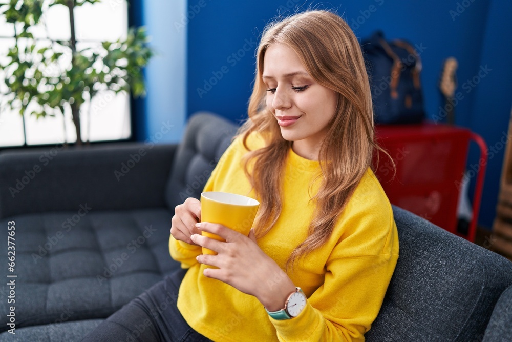 Young blonde woman drinking coffee sitting on sofa at street Young blonde woman drinking coffee sitting on sofa at street
