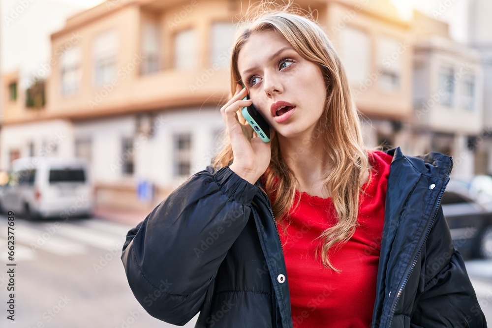 Young blonde woman talking on smartphone with serious expression at street Young blonde woman talking on smartphone with serious expression at street