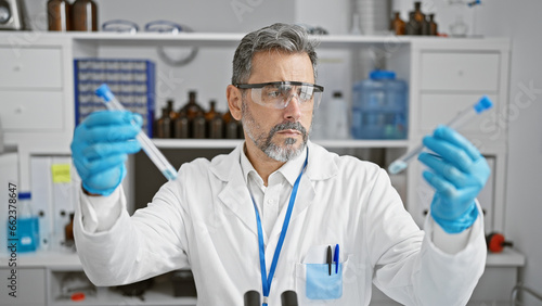 Handsome  young hispanic man  a grey-haired scientist  engrossed in critical medical research at his lab  judiciously measuring liquid in test tubes  embodying professionalism and precision.