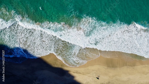 lone surfer with friend from sky vantage secluded beach Kauai
