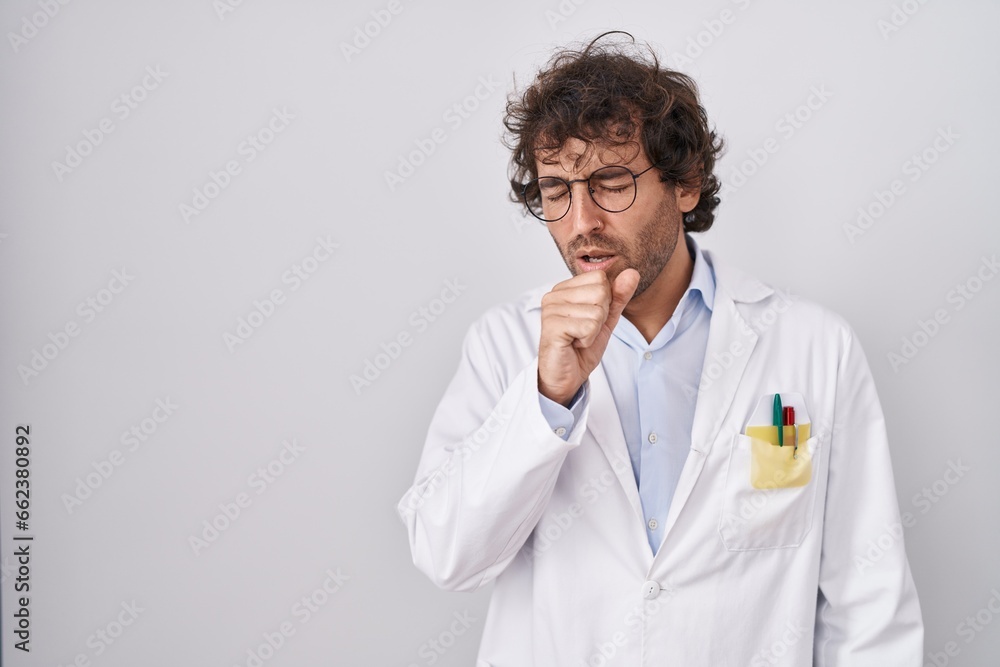 Hispanic young man wearing doctor uniform feeling unwell and coughing as symptom for cold or bronchitis. health care concept. Hispanic young man wearing doctor uniform feeling unwell and coughing as symptom for cold or bronchitis. health care concept.