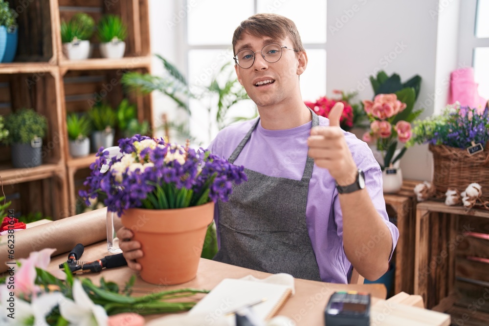 Caucasian blond man working at florist shop pointing fingers to camera with happy and funny face. good energy and vibes.