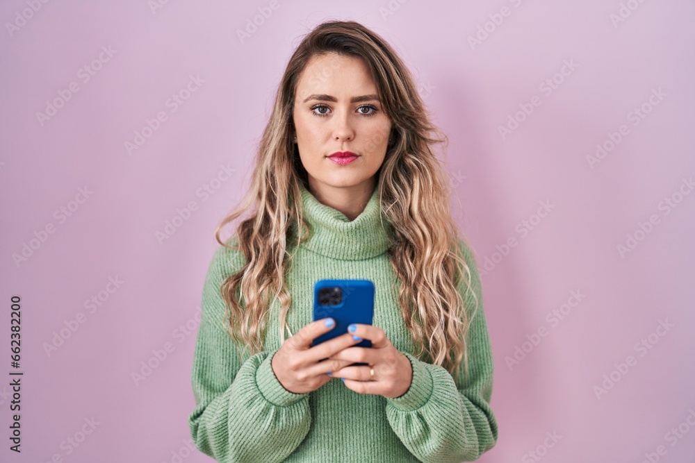 Young caucasian woman using smartphone typing message relaxed with serious expression on face. simple and natural looking at the camera. Young caucasian woman using smartphone typing message relaxed with serious expression on face. simple and natural looking at the camera.