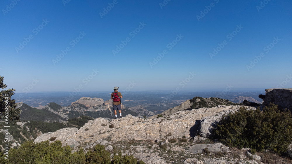 The man standing on the cliff. The hiker climbed to the rocky summit and enjoyed the views of the valley. A man looks at the clear sky in the morning sun. The man standing on the cliff. The hiker climbed to the rocky summit and enjoyed the views of the valley. A man looks at the clear sky in the morning sun.