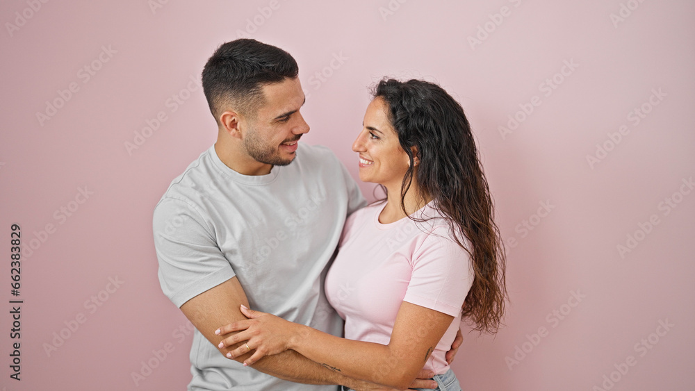Man and woman couple smiling confident hugging each other over isolated pink background Man and woman couple smiling confident hugging each other over isolated pink background