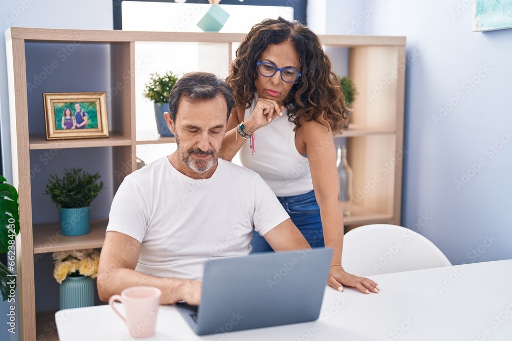 Man and woman couple using laptop with serious expression at home Man and woman couple using laptop with serious expression at home