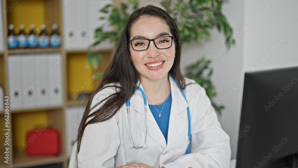 Young beautiful hispanic woman doctor using computer smiling at the clinic Young beautiful hispanic woman doctor using computer smiling at the clinic