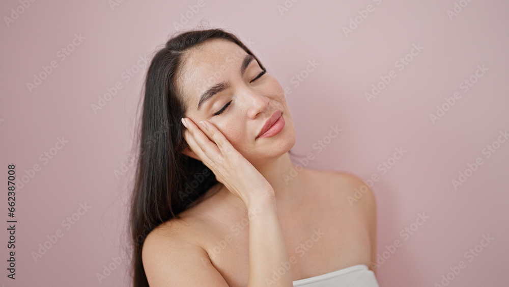 Young beautiful hispanic woman smiling confident touching face over isolated pink background Young beautiful hispanic woman smiling confident touching face over isolated pink background