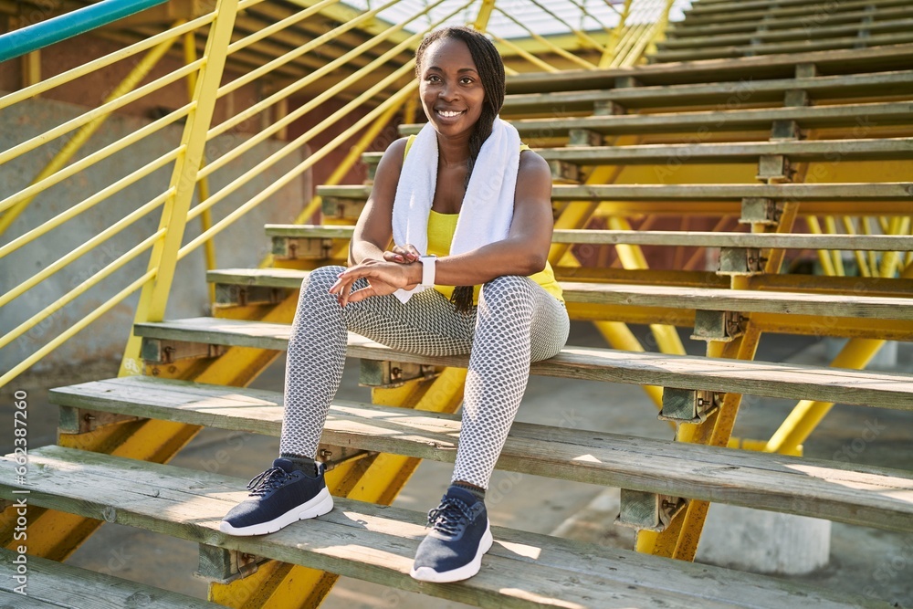 African american woman using stopwatch sitting on stairs at street African american woman using stopwatch sitting on stairs at street