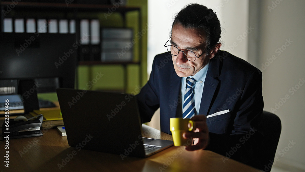 Middle age man business worker using laptop drinking coffee at the office Middle age man business worker using laptop drinking coffee at the office