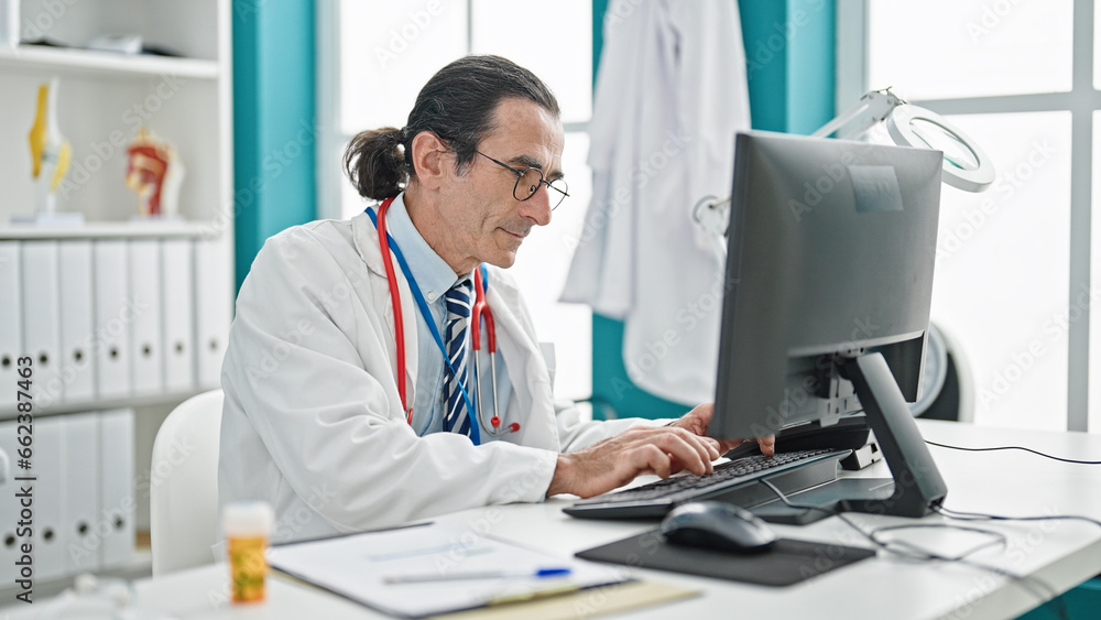 Middle age man doctor using computer at the clinic