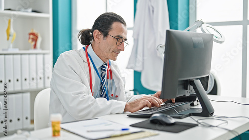 Middle age man doctor using computer at the clinic