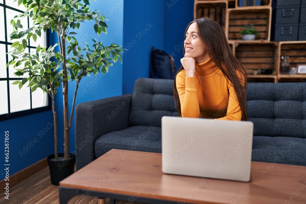 Obraz premium Young beautiful hispanic woman using laptop sitting on sofa at home