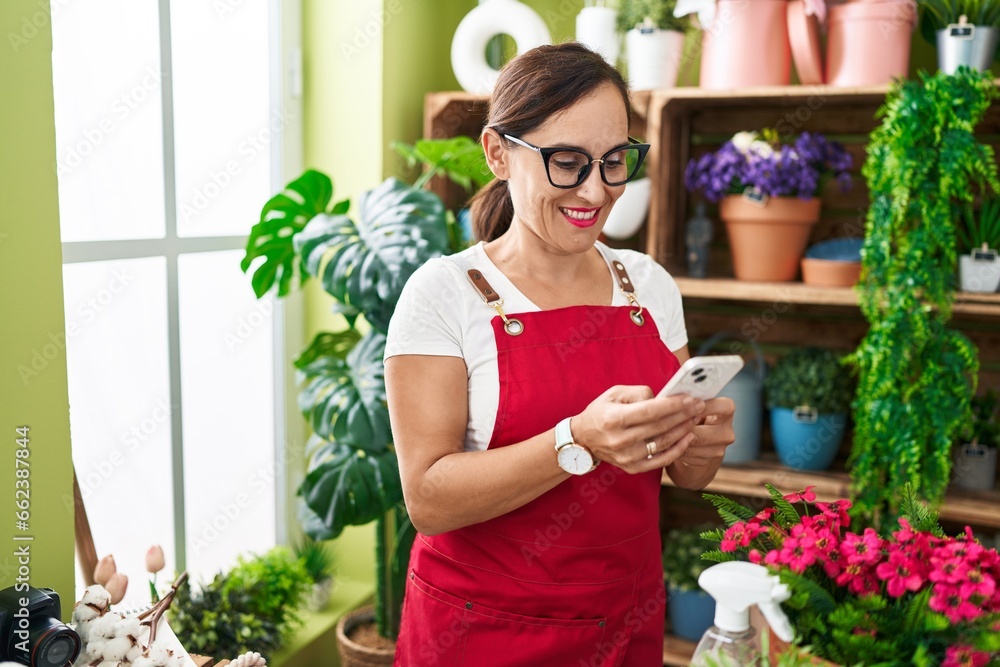 Young beautiful hispanic woman florist smiling confident using smartphone at flower shop