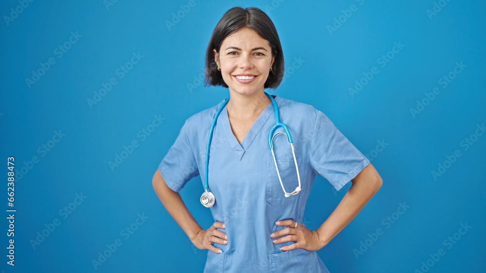 Young beautiful hispanic woman doctor smiling confident standing over isolated blue background Young beautiful hispanic woman doctor smiling confident standing over isolated blue background