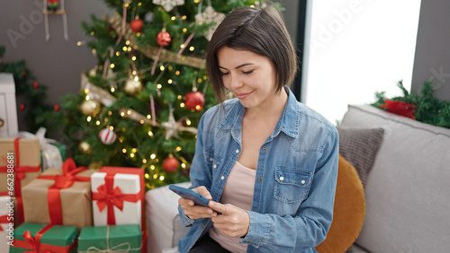 Young caucasian woman using smartphone sitting on the sofa at home