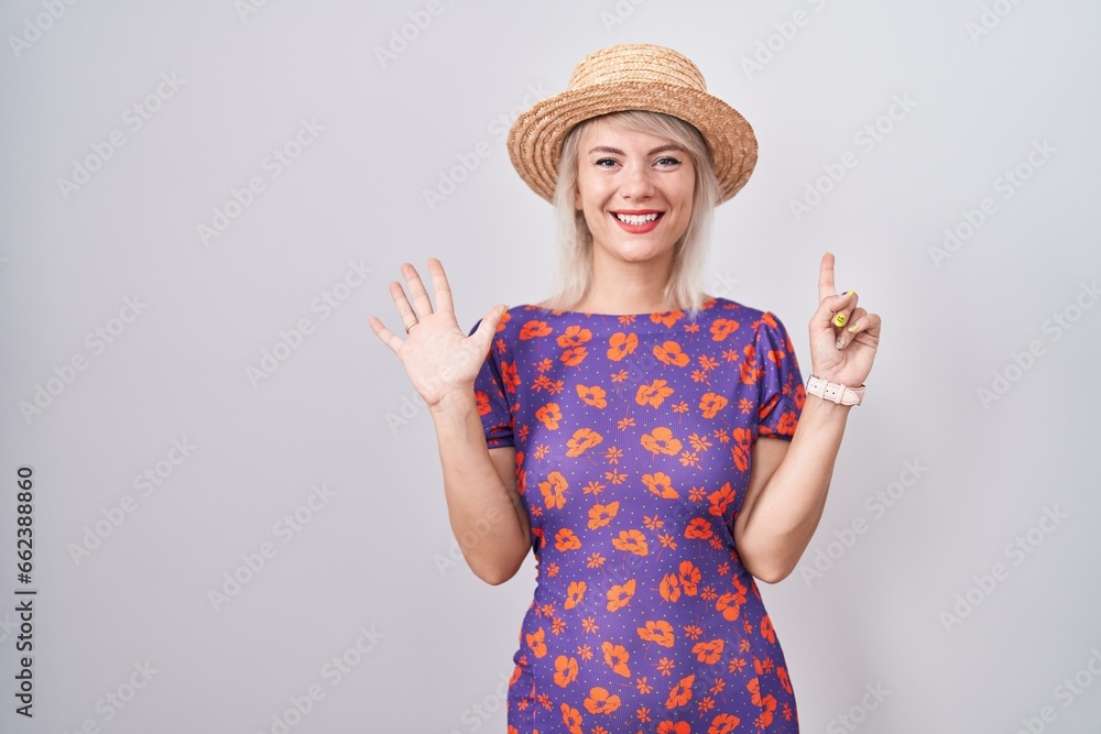 Young caucasian woman wearing flowers dress and summer hat showing and pointing up with fingers number six while smiling confident and happy. Young caucasian woman wearing flowers dress and summer hat showing and pointing up with fingers number six while smiling confident and happy.