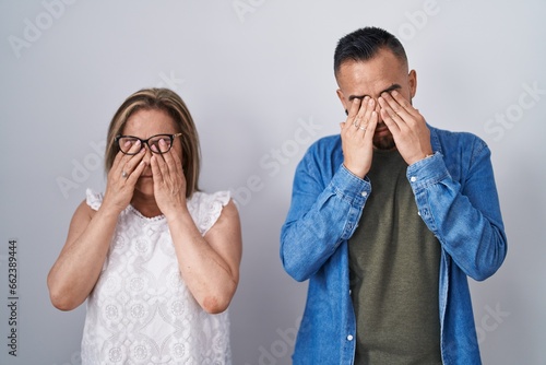 Hispanic mother and son standing together rubbing eyes for fatigue and headache, sleepy and tired expression. vision problem