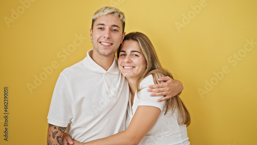 Beautiful couple smiling confident hugging each other over isolated yellow background © Krakenimages.com