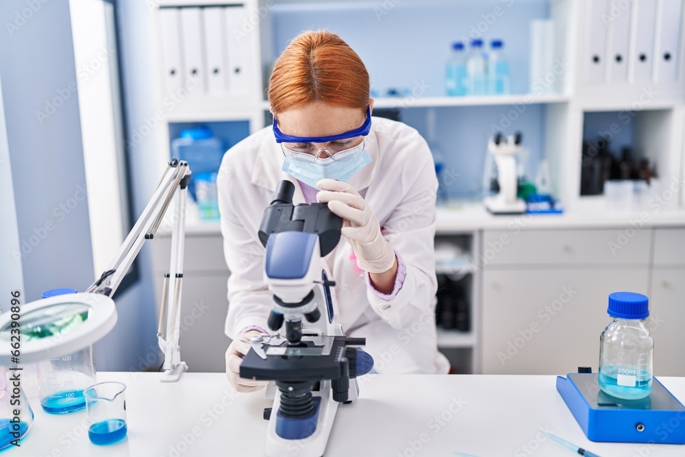 Young caucasian woman scientist wearing medical mask using microscope at laboratory Young caucasian woman scientist wearing medical mask using microscope at laboratory