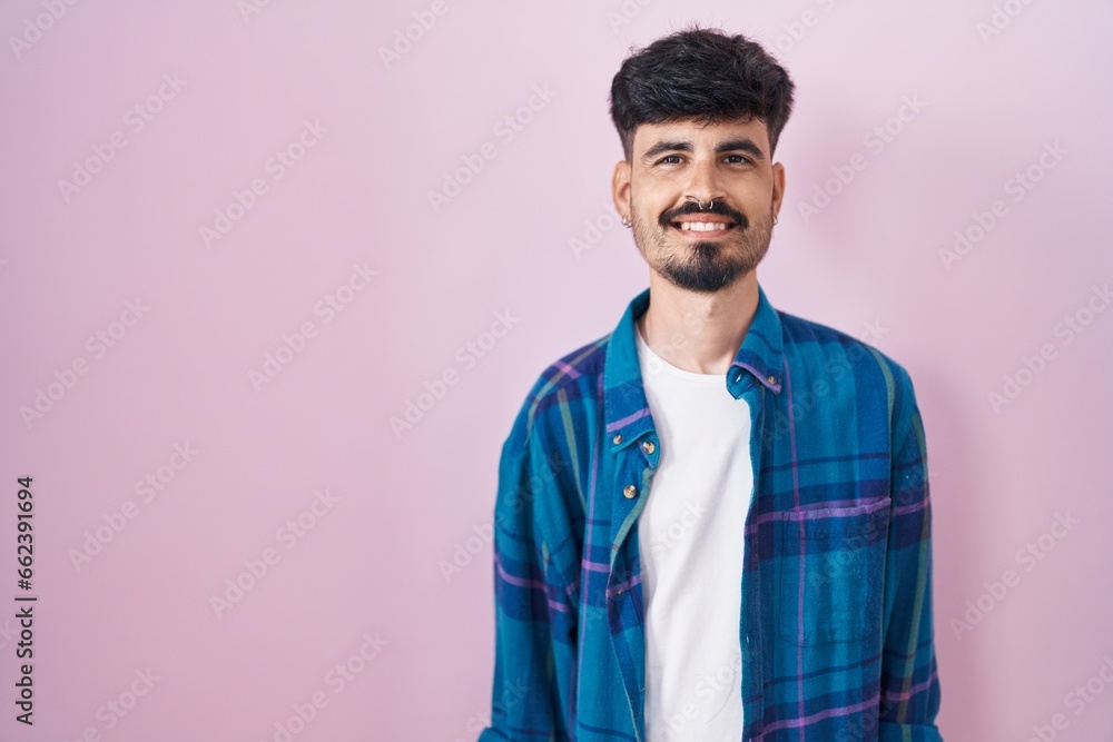 Young hispanic man with beard standing over pink background with a happy and cool smile on face. lucky person. Young hispanic man with beard standing over pink background with a happy and cool smile on face. lucky person.