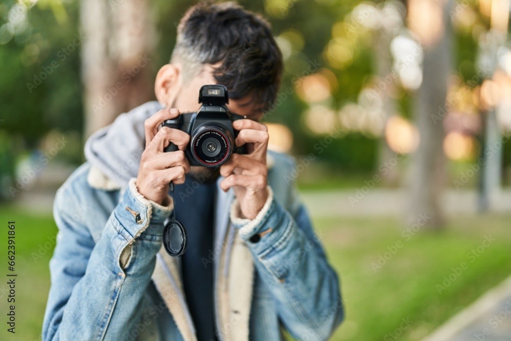 Young hispanic man using professional camera at park Young hispanic man using professional camera at park