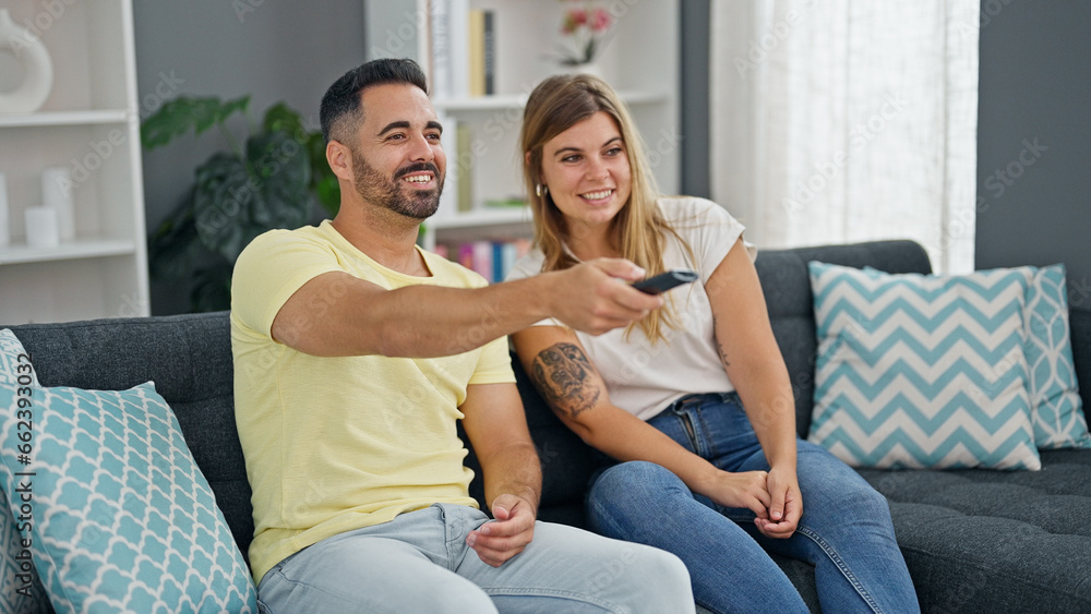 Obraz premium Man and woman couple sitting on sofa watching television at home