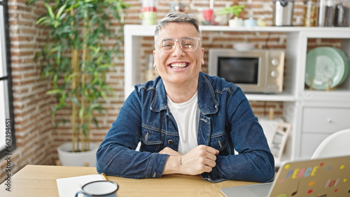 Young caucasian man smiling confident sitting on table at dinning room