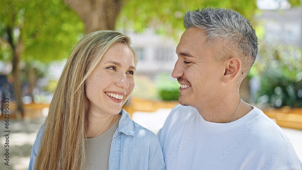 Man and woman couple looking each other standing together at park Man and woman couple looking each other standing together at park