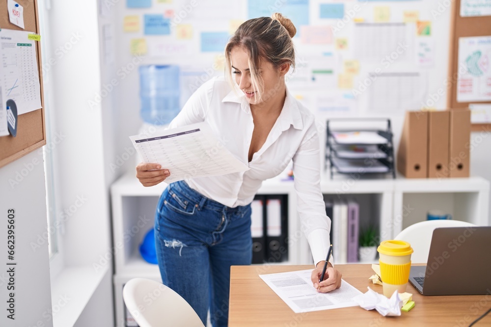 Young blonde woman business worker writing on document standing at office Young blonde woman business worker writing on document standing at office