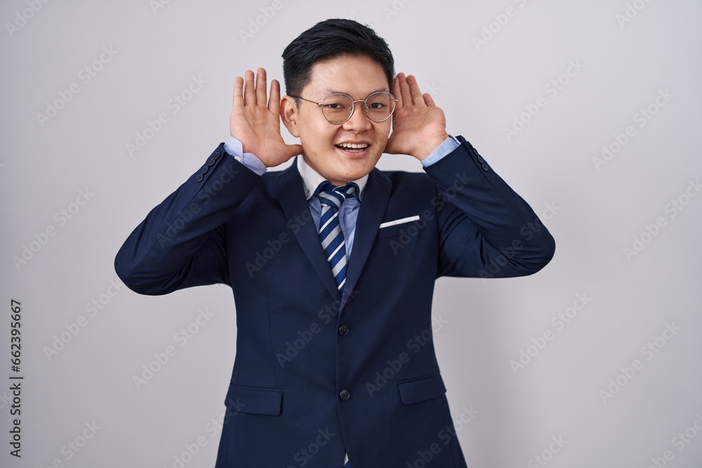 Young asian man wearing business suit and tie smiling cheerful playing peek a boo with hands showing face. surprised and exited Young asian man wearing business suit and tie smiling cheerful playing peek a boo with hands showing face. surprised and exited