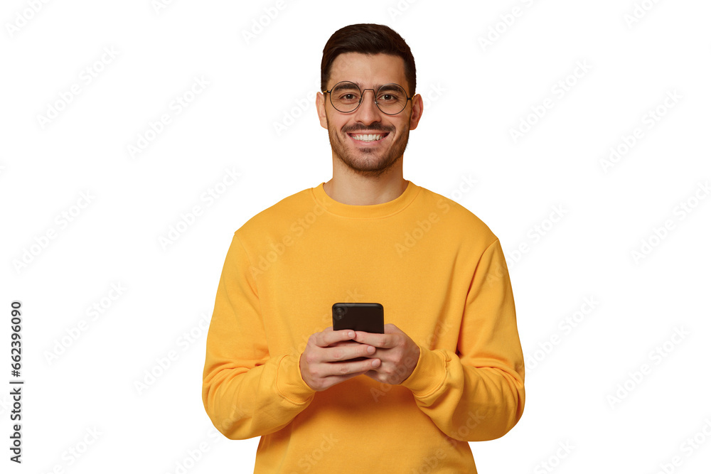 Young man wearing yellow sweatshirt, standing in front of camera with phone in hands Young man wearing yellow sweatshirt, standing in front of camera with phone in hands