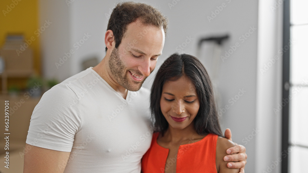 Fototapeta premium Beautiful couple hugging each other looking down smiling at new home