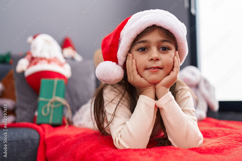 Adorable hispanic girl wearing christmas hat lying on sofa at home Adorable hispanic girl wearing christmas hat lying on sofa at home