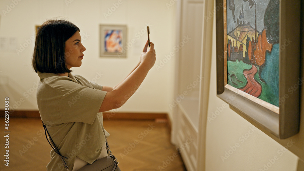 Young beautiful hispanic woman visiting art gallery taking pictures with smartphone at Belvedere Palace in Vienna - obrazy, fototapety, plakaty 
