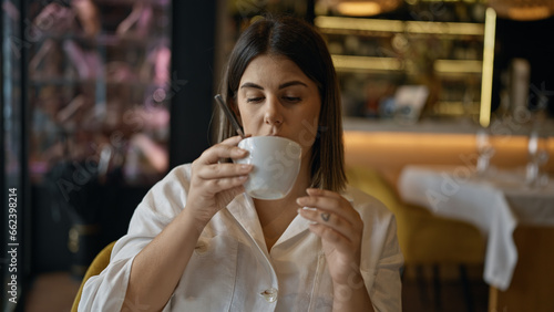 Young beautiful hispanic woman drinking coffee sitting on the table at the restaurant