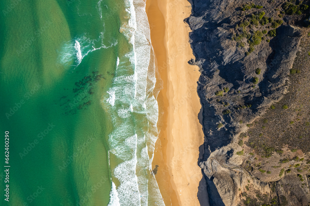 Sandy beach and dramatic cliffs on Atlantic Ocean coastline in Portugal. Aerial drone view Sandy beach and dramatic cliffs on Atlantic Ocean coastline in Portugal. Aerial drone view