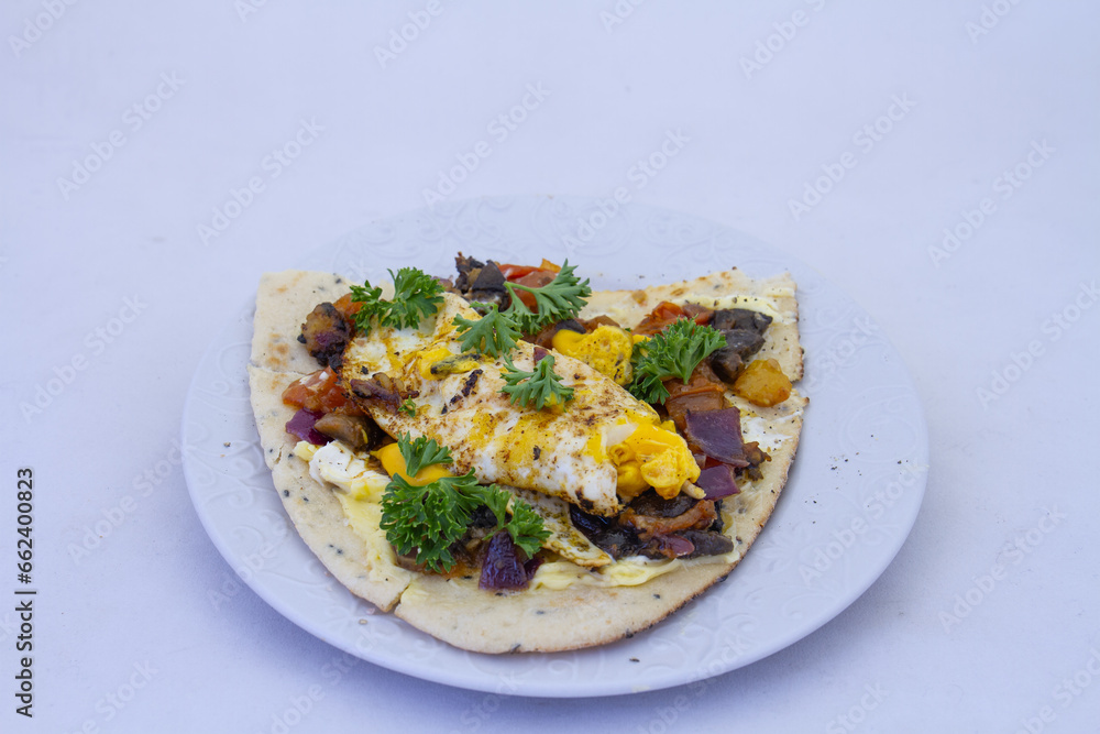 Fried egg and roasted vegetables on naan bread isolated on a plate on a clear background with copy space Fried egg and roasted vegetables on naan bread isolated on a plate on a clear background with copy space
