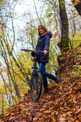 A young woman with a bicycle on a forest trail in the autumn forest