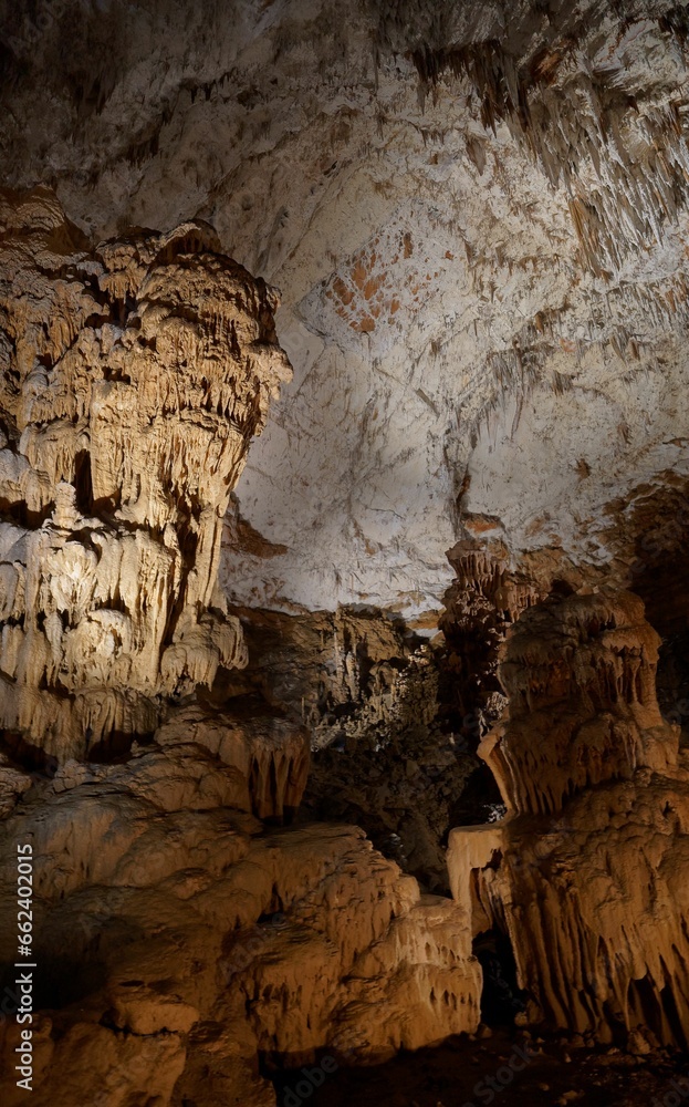 Breathtaking entrance to a natural limestone cave, situated by a tranquil body of water