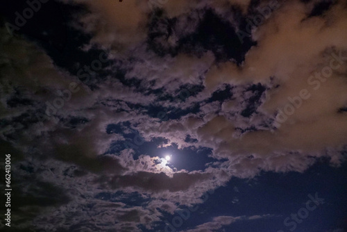 Full moon and white cloudy sky at dusk, beautiful full moon photo, sky photo under the light of the moon in summer, romantic photo idea, nature concept.
