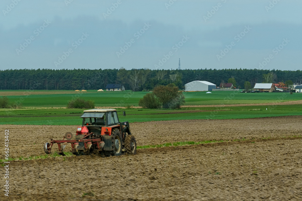Fototapeta premium A tractor with plows stands near a plowed field.