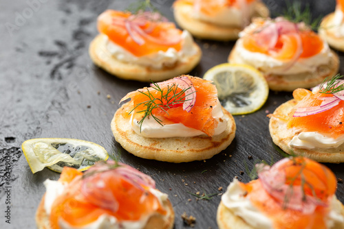 Mini blini pancakes with soft cheese, cold smoked salmon and dill photo
