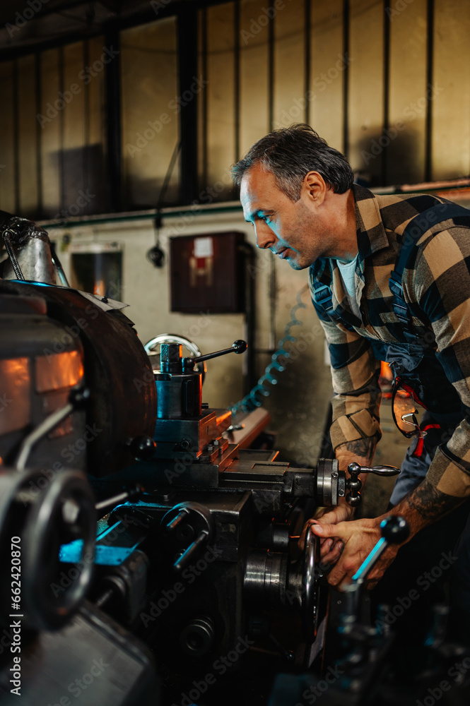 Portrait frame of a machinist operating a lathe machine in a factory. Portrait frame of a machinist operating a lathe machine in a factory.