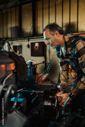 Portrait frame of a machinist operating a lathe machine in a factory.